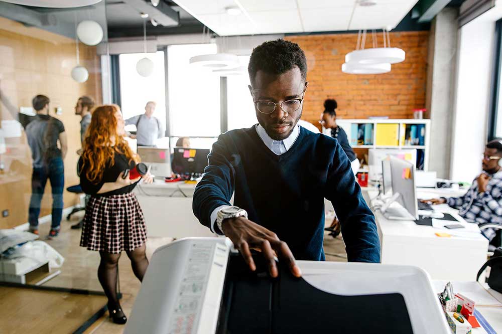 Une équipe au travail autour d’un multifonction en open space.